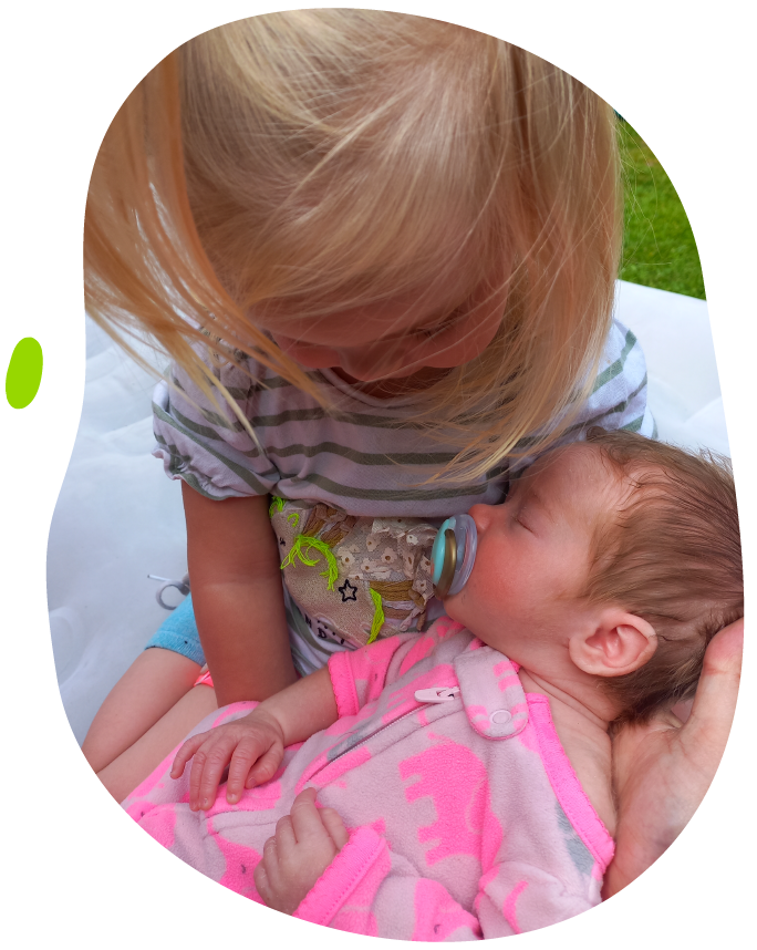 Katie with sister being cradled - Katie's Mito Mission